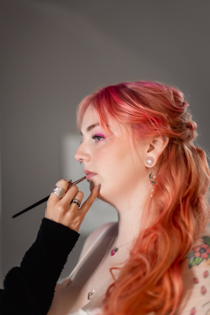 bride with pink red hair having make up applied