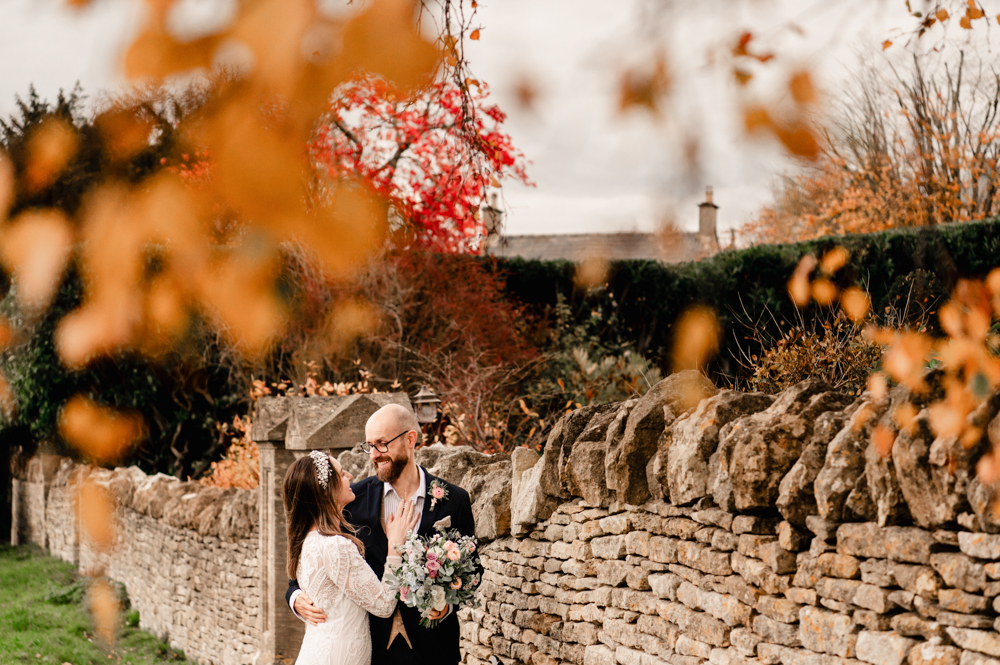 bride and groom kissing   autumn cotswold stone wall