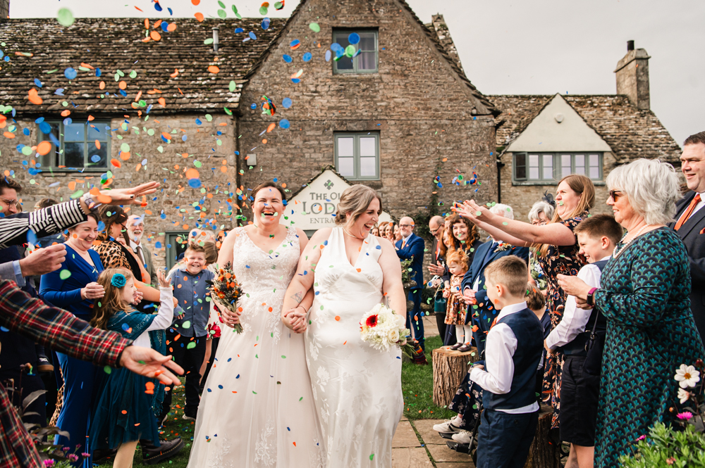 two brides walking under colourful confetti stroud wedding