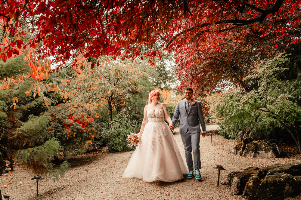 bride and groom walking in a colourful autumn garden at Matara centre cotswolds