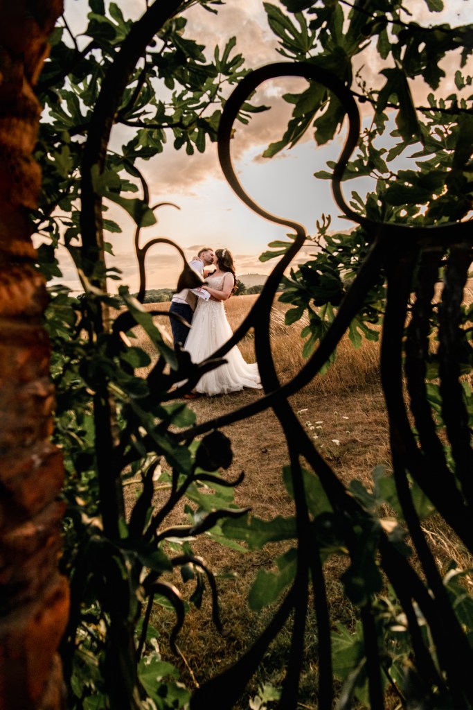 wedding couple through an ornate gate sunset portrait
