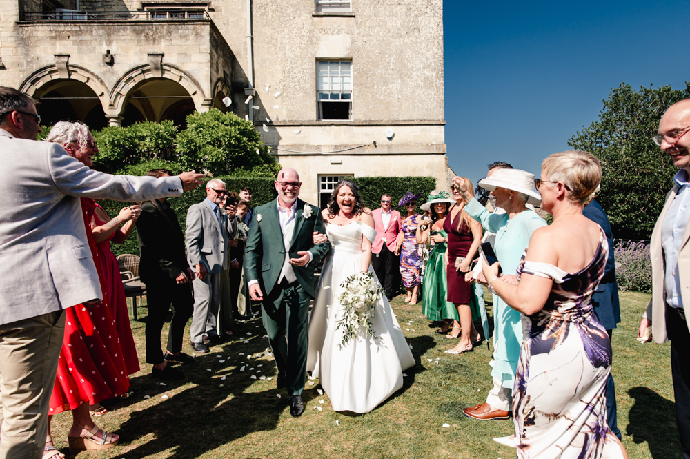 bride and groom walking through confetti manor hotel The Painswick