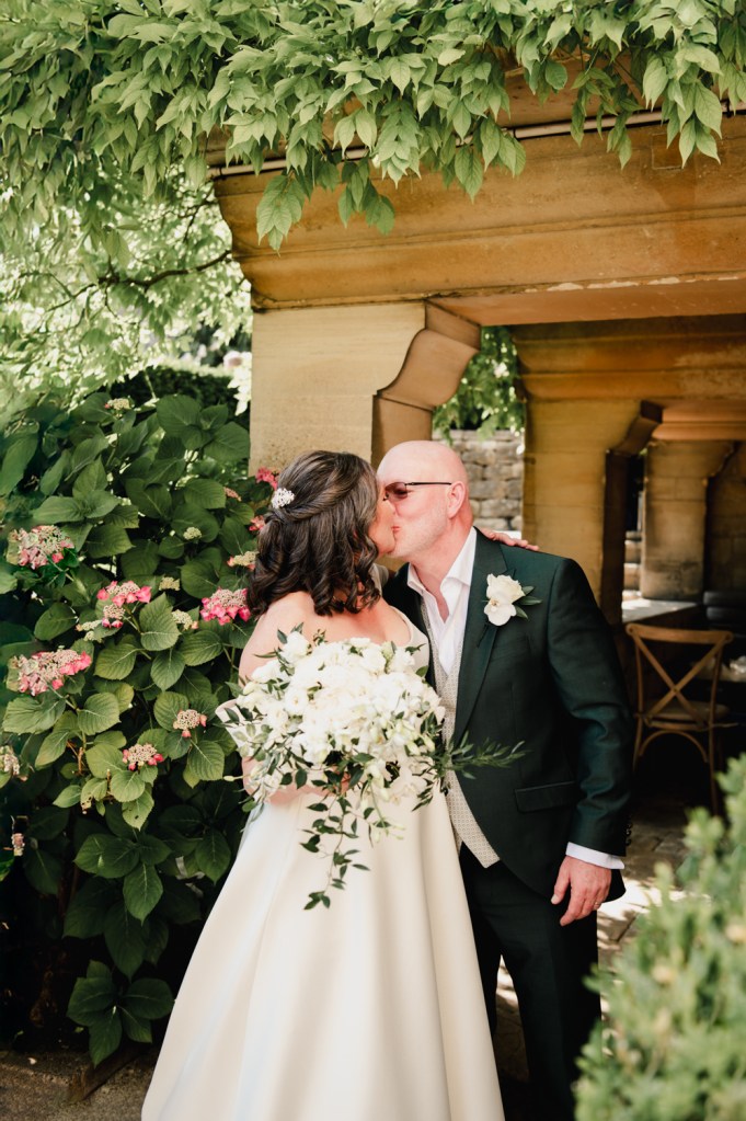bride and groom kissing in a manor garden