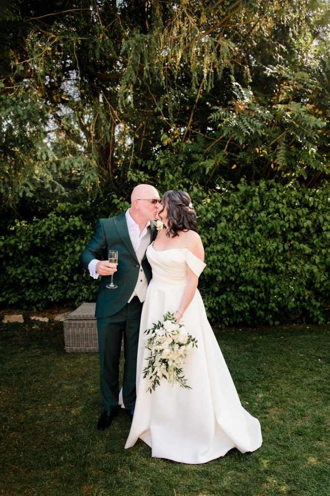 groom in a green suit kissing bride
