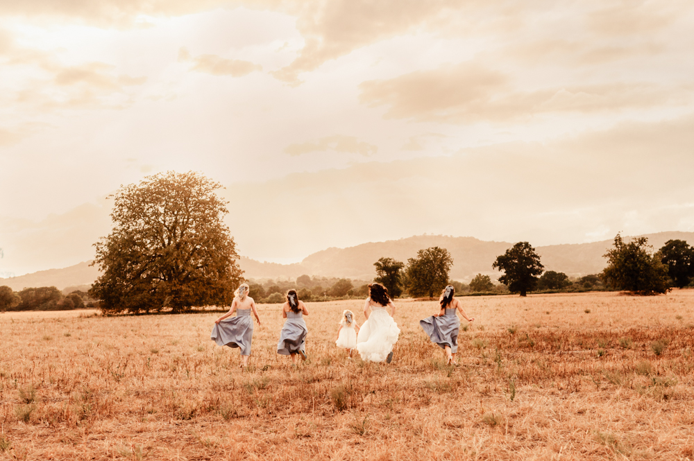 bridesmaids running in a field cotswold wedding