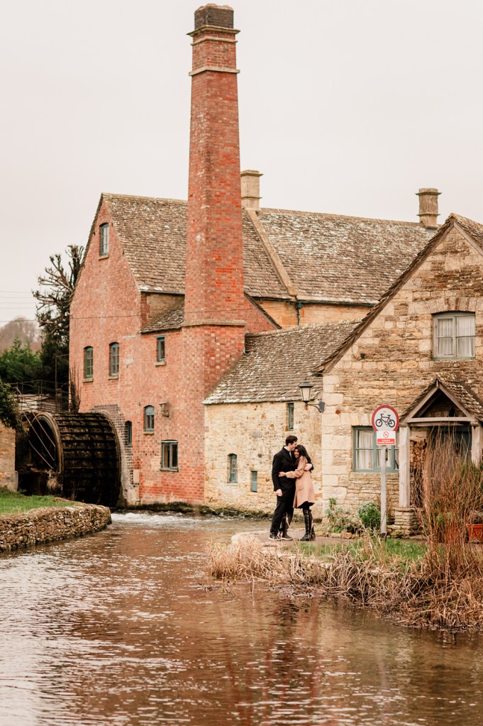 couple by an old mill in a cotswold village