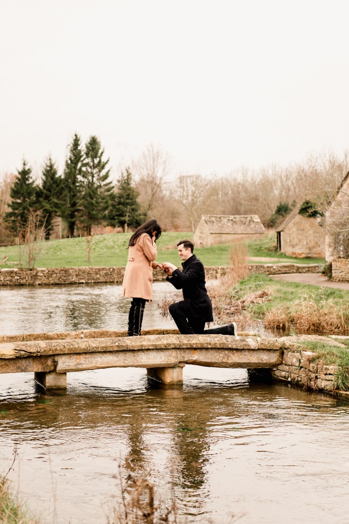 man on one knee proposing on a bridge in england