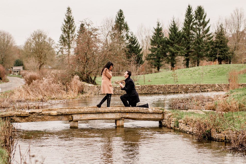 man proposing on a bridge in a picturesque cotswold village in England