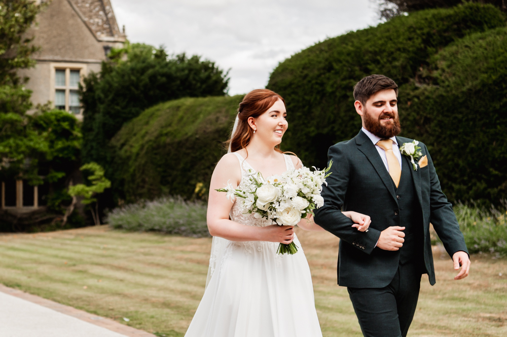 Bride and groom walking in the garden of The Greenway Hotel 