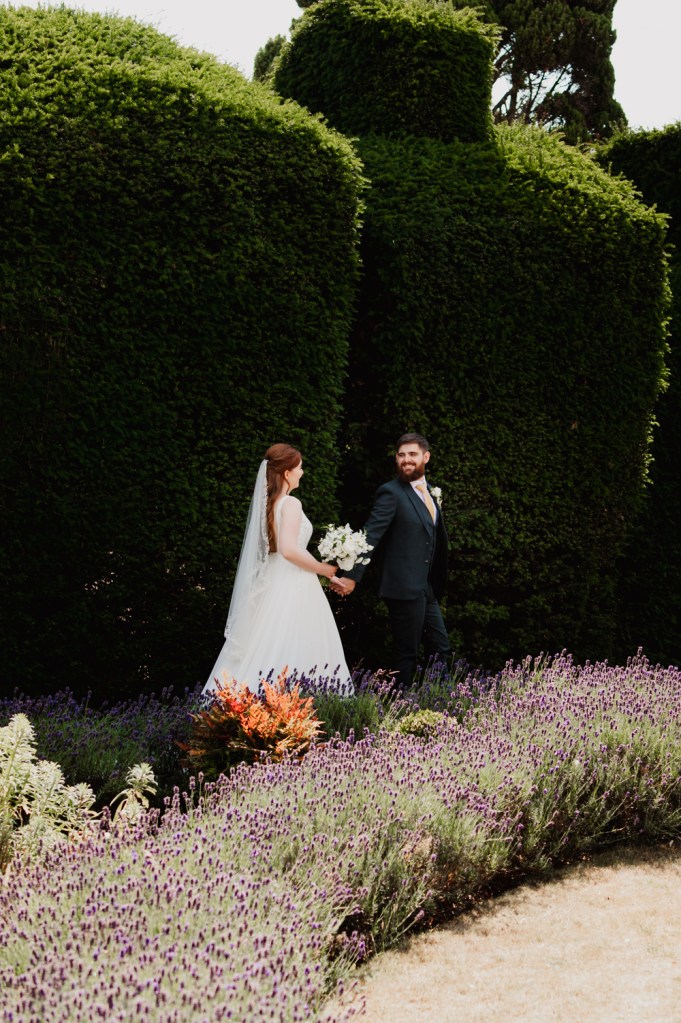 Bride and groom walking in the garden of The Greenway Hotel after their elopement wedding ceremony