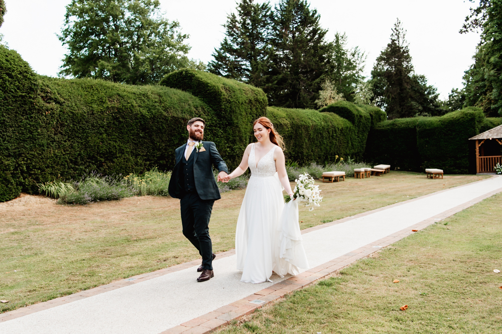 Bride and groom walking in the garden of a manor house hotel in the cotswolds