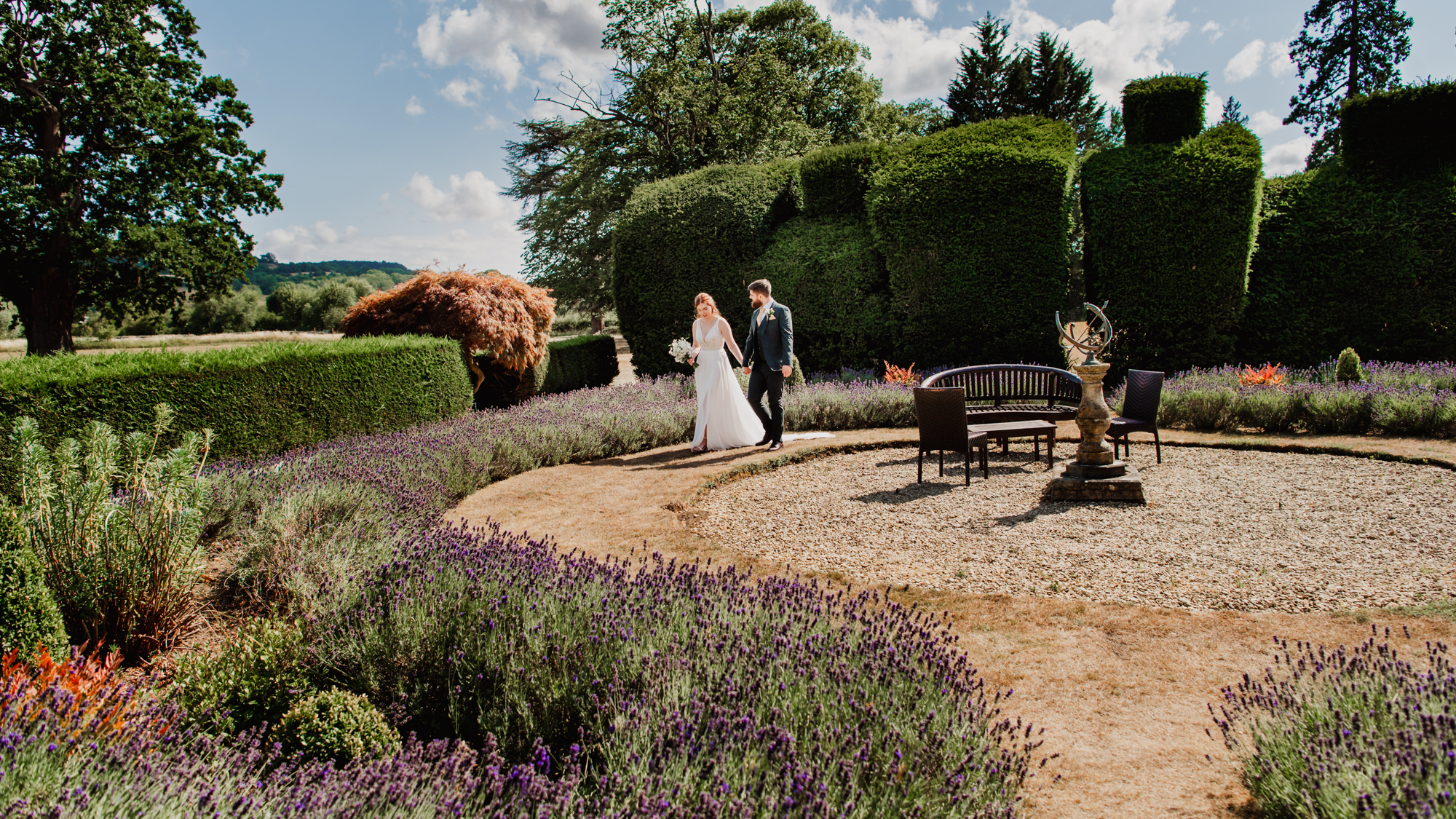 Bride and groom walking in a lavender garden captured by Cotswold wedding photographer