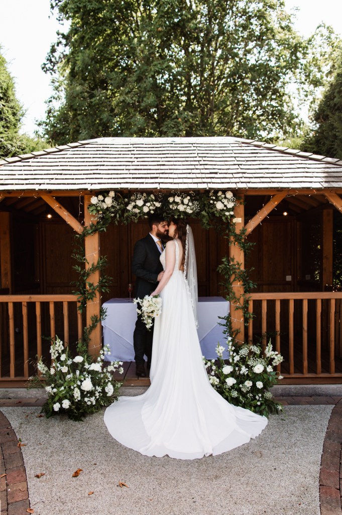 Bride and groom kissing in the garden of a manor hotel  captured by Cotswolds wedding photographer