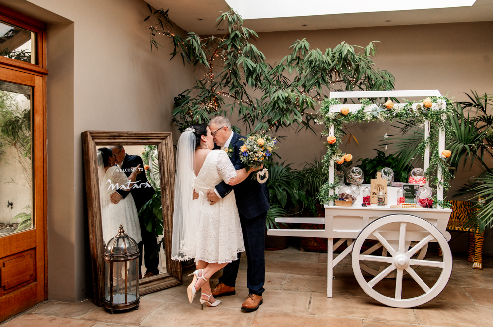 elegant older bride and groom posing next to a sweet cart