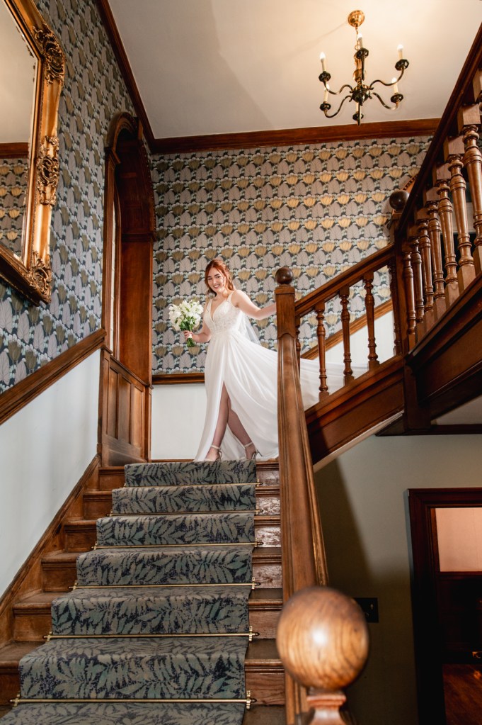 Bride walking down the stairs at The Greenway Hotel captured by Cotswolds wedding photographer