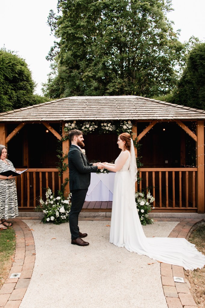 Bride and groom getting married in the garden of The Greenway Hotel captured by Cotswolds wedding photographer