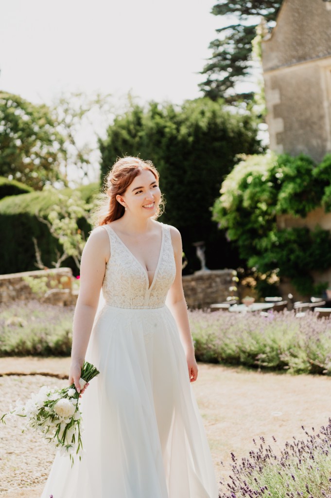 Bride walking in the garden of Greenway Hotel captured by Cotswold wedding photographer