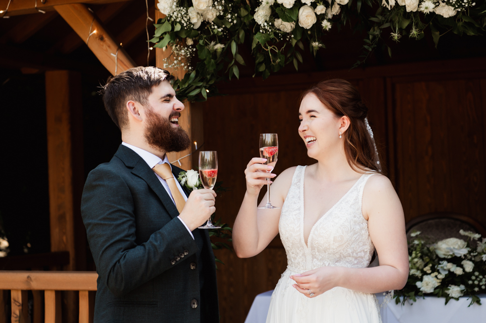 Bride and groom having a celebratory drink captured by Cotswold wedding photographer