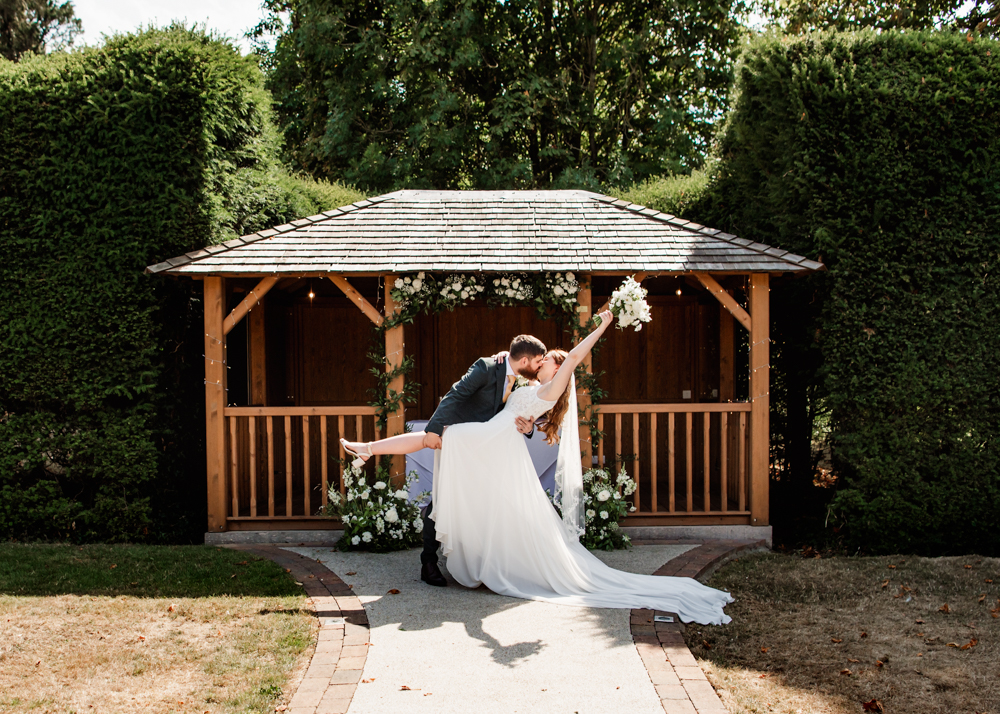 Bride and groom kissing in the garden  captured by Cotswolds wedding photographer